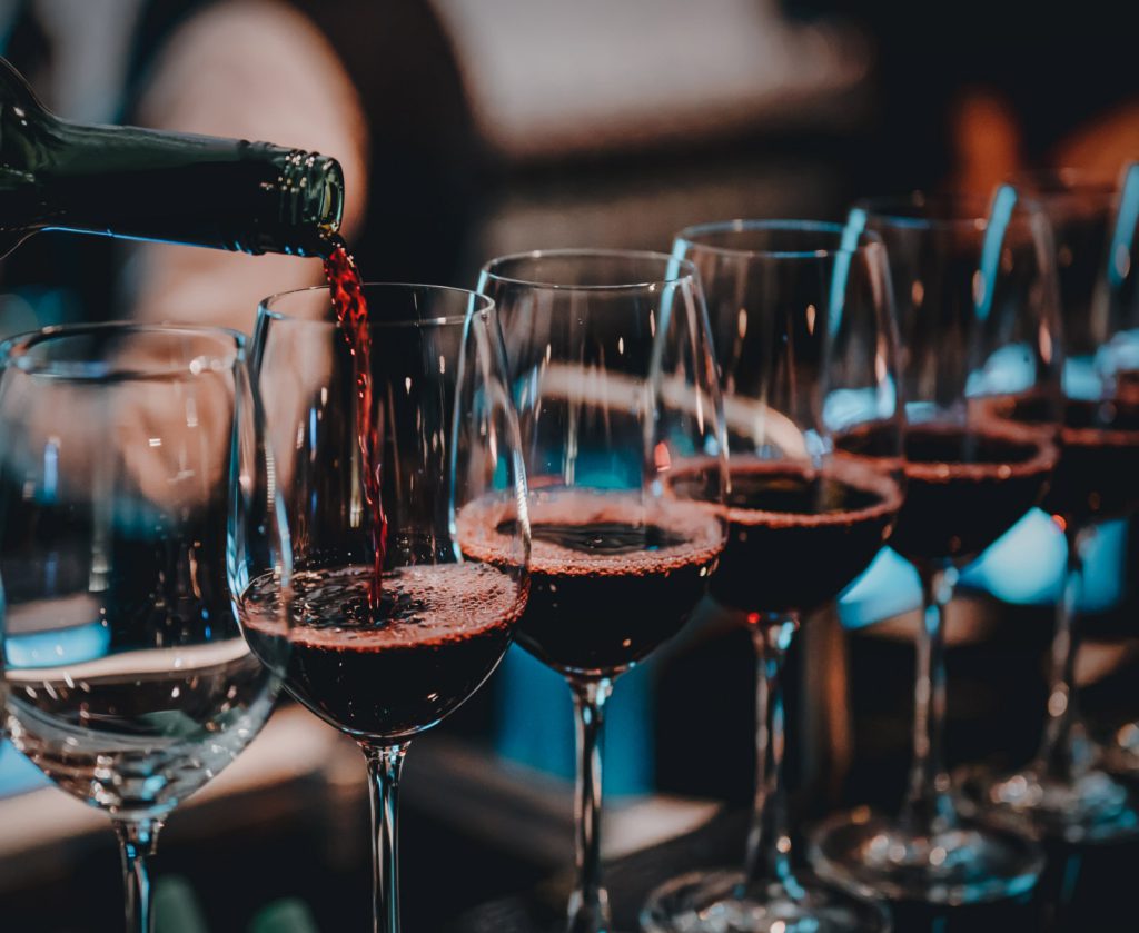 Calici in fila che stanno riempiendo con vino