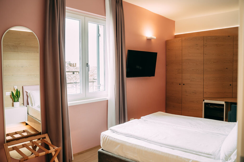 interno camera con letto, tv, finestra